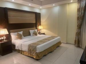 a bedroom with a large bed and two lamps at رولانا للشقق المخدومة Rolana Serviced Apartments in Jeddah +29 photos