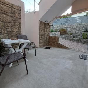 a patio with two chairs and a table and a stone wall at Simos in Vrontádos