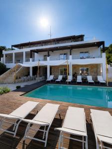 a villa with a swimming pool and lounge chairs at Mercury Beach Hotel in SantʼAntìoco
