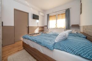 a bedroom with a bed with a blue comforter and a window at Varga Vendégház in Tótszerdahely