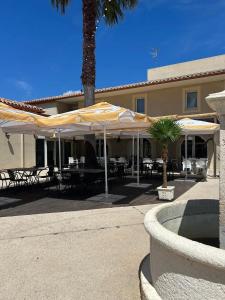 a patio with tables and umbrellas in front of a building at Maison coquette camarguaise in Codognan