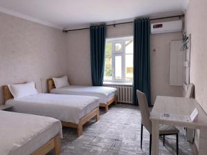 a room with two beds and a table and a window at Tabylga guest house in Jalal-Abad