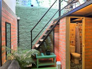 a bathroom with a staircase next to a brick wall at La Gruta Coliving in Medellín