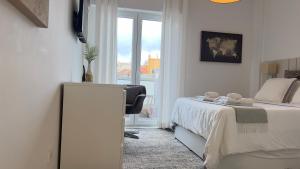 a white bedroom with a bed and a window at Quarto com casa de banho privativo in Amadora