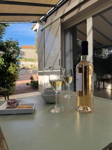 a bottle of wine and two glasses on a table at Patios di pruno Suite MELO in Figari