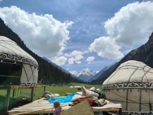 a group of tents in a field with mountains at Kyrgyz Yurt Camp in Mineralʼnyy Istochnik Altyn-Arasan