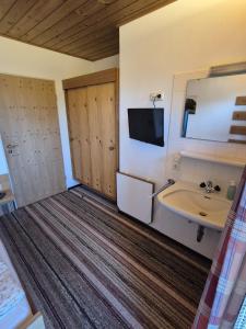 a bathroom with a sink and a tv on the wall at Gästehaus Nigg in Eisenberg