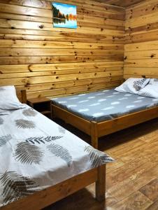 two beds in a room with wooden walls at Krainya hata in Melʼniki