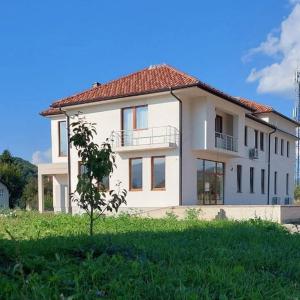 a large white house with a green field in front of it at Apartmani Han in Bijelo Polje