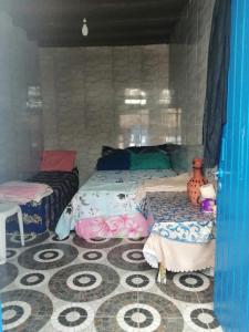 a bedroom with two beds and a table and a floor at Grotte de pêcheurs Tigri in Aglou