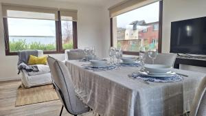 a dining room with a table with chairs and a television at Jardin de Estepa Il in Dina Huapi