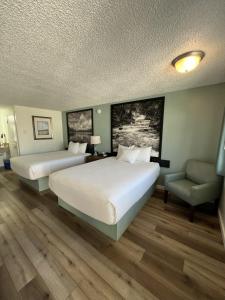 a hotel room with two beds and a chair at Super 8 by Wyndham Florence OR in Florence