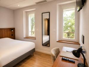 a bedroom with a bed and a desk and a mirror at Le Relais de la Calèche in Le Beausset