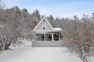a white house with snow on the ground at Cozy Villager in Stowe