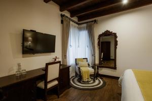ein Schlafzimmer mit einem Bett, einem Schreibtisch und einem Spiegel in der Unterkunft Los Pasos Boutique Hotel & Spa in Antigua Guatemala
