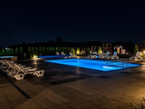 a swimming pool at night with lounge chairs around it at Domki La Plata in Łeba