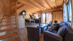 a man sitting on a couch in a tiny house at Domki La Plata in Łeba +42 photos