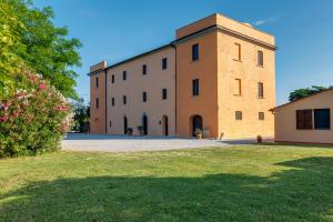 a large brick building with a grass yard in front of it at Agriturismo Il Pescinone in Venturina Terme