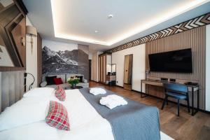 a hotel room with a large white bed with a desk at Rysy Boutique Hotel in Zakopane +140 photos