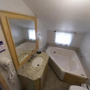 a bathroom with a tub and a sink and a large mirror at Pousada Agradável Pomerode in Pomerode +25 photos