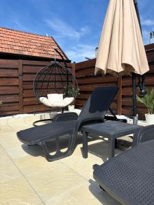 a patio with two chairs and an umbrella and a swing at Vila Jovanovic in Bajina Bašta