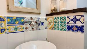 a bathroom with a toilet with colorful tiles on the wall at Nel Borgo di San Francesco - Ospitalità Diffusa - Relax tra Roccaraso e Costa dei Trabocchi in Villa Santa Maria +22 photos
