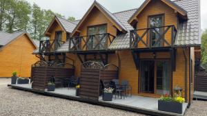 a wooden house with a balcony and tables and chairs at Andiland in Karwia