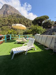 a patio with chairs and an umbrella on the grass at villa Cycas in Maratea