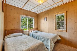 two beds in a room with two windows at Cabin #9 2BR 1BA Timberlane Resort in Park Rapids