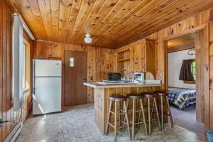 a kitchen with a refrigerator and bar with stools at Cabin #10 2BR 1BA Timberlane Resort in Park Rapids