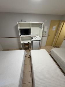 a room with two beds and a desk and a chair at Hotel Itapoã in Teresina