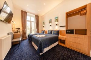 a hotel room with a bed and a flat screen tv at Jubilee Hotel Victoria in London