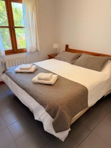 a bedroom with a large bed with two towels on it at Hostería Bärenhaus in San Martín de los Andes