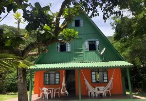 a house with a green roof with chairs in front at Chalé frente mar na Ilha do Mel - Encantadas. in Ilha do Mel