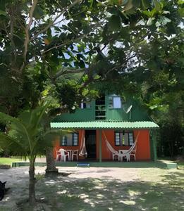 an orange and green house with tables and chairs at Chalé frente mar na Ilha do Mel - Encantadas. in Ilha do Mel +34 photos