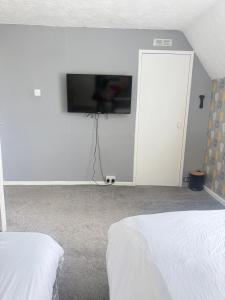 a bedroom with two beds and a flat screen tv on the wall at Families and Contractors Dudley DY1 in Lower Gornal