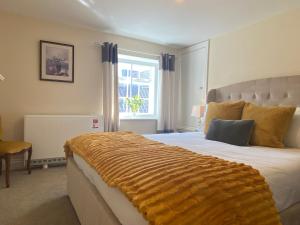 a bedroom with a large bed with a yellow blanket on it at Spa View Apartments in Ripon