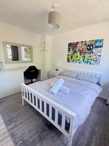 a bedroom with a white bed with a painting on the wall at Families and Contractors Dudley DY1 in Lower Gornal