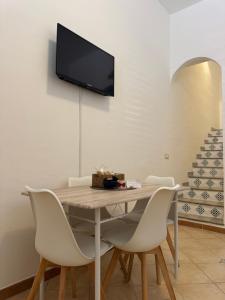 a dining room table with chairs and a tv on the wall at Sicilia Bedda Holiday Home in Cinisi