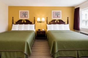two beds in a hotel room with green sheets at Lincoln Way Inn in Chambersburg