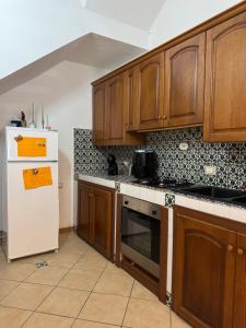 a kitchen with wooden cabinets and a white refrigerator at Sicilia Bedda Holiday Home in Cinisi
