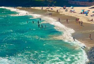 a group of people on a beach near the water at Hotel Siroco Portonovo in Sanxenxo