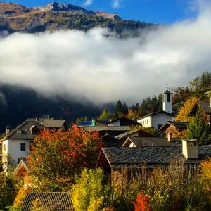 a village in the mountains with clouds in the background at Himalayan vibes in Icogne