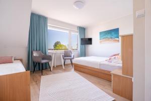 a bedroom with two beds and a desk and a window at Magdalena in Karwia