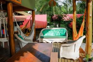 a porch with chairs and a table and hammocks at Casa da Ale e do Thi - Ilha do Mel in Ilha do Mel