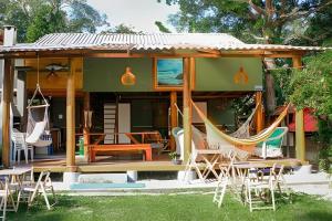 a house with chairs and hammocks in the yard at Casa da Ale e do Thi - Ilha do Mel in Ilha do Mel