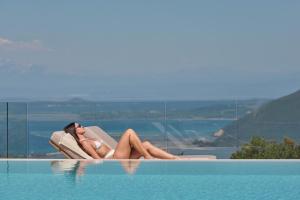 a woman sitting in a chair next to a swimming pool at Anemones Villas by Omikron Selections in Spanokhórion