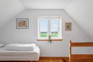 a white room with a bed and a window at 6707-Ronne-Kallokkevej-5 in Rønne