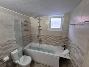 a white bathroom with a tub and a toilet at Salve Suite in Lefkada