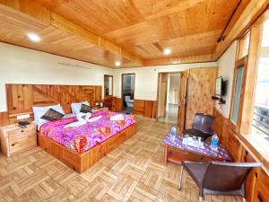 a bedroom with a large bed and a wooden ceiling at Katha Inn in Manāli